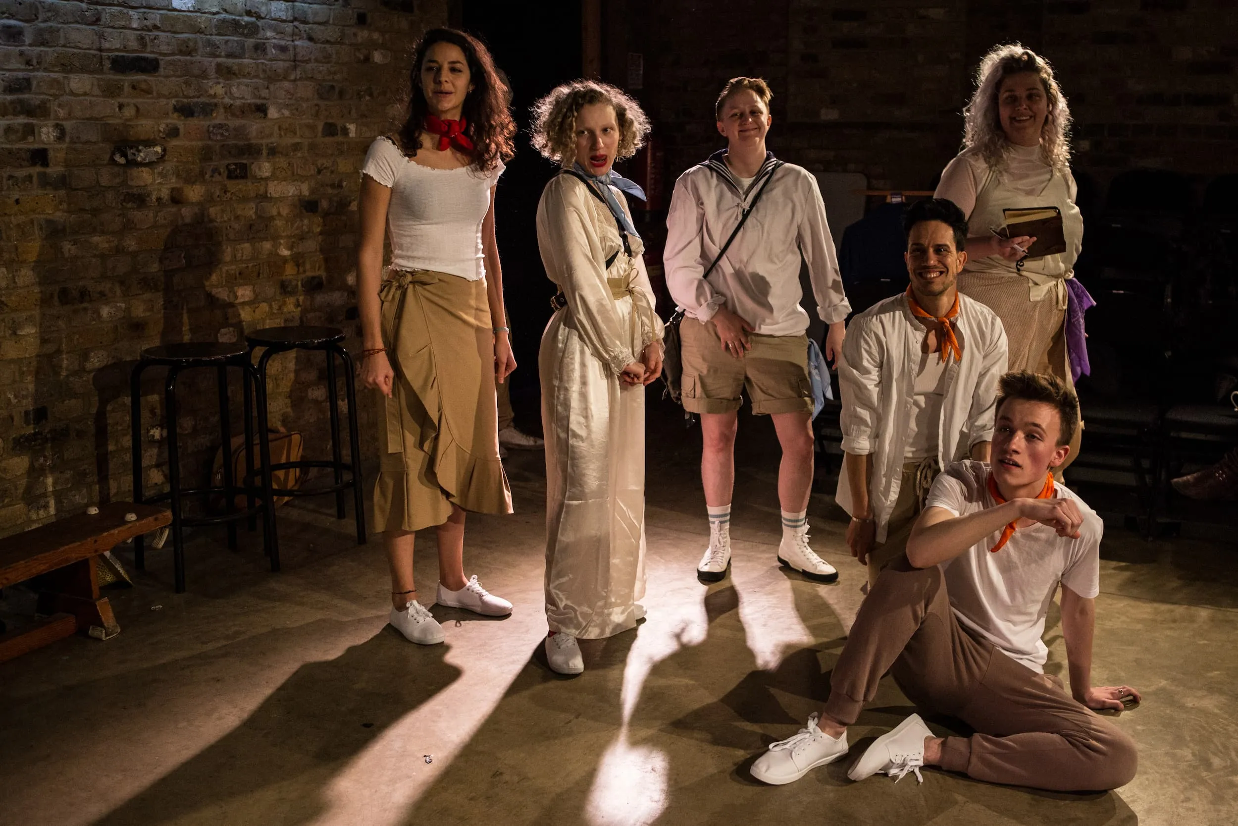 A group of six smiling people, backlit in neutral light, cast long shadows towards the viewer